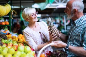 A photo of a mature couple shopping for fruit at the grocery store.