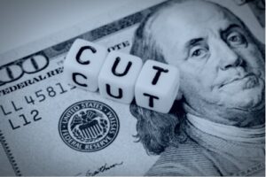 A concept image showing the word “cut” near the Federal Reserve symbol on a $100 bill.