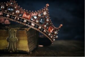 A photo showing a bejeweled crown resting atop a book.