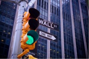 A photo showing a traffic signal with a green light at a Wall Street intersection.