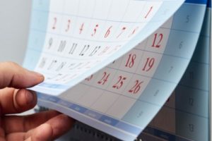 A photo showing a person’s hand flipping through the pages of a calendar.