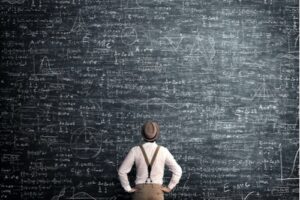 A photo showing a man standing in front of a blackboard contemplating a complex equation.