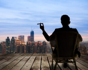 A businessman smokes a cigar and looks out at a city skyline