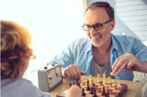 A photo showing a grandfather and grandson playing chess.