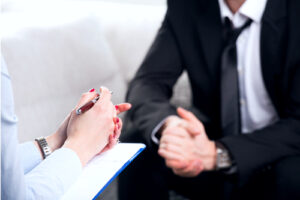 A photo showing a well-dressed male patient sitting in discussion with a female psychiatrist.