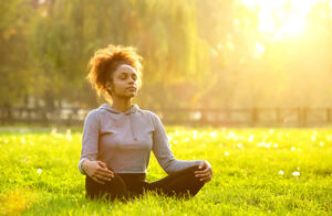 A woman meditates in the grass