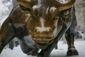 A photo of the charging bull statue in Manhattan during a snowy day.