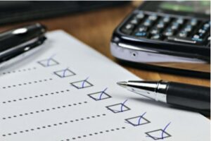 A photo showing a completed checklist on a desk with a pen and calculator nearby.