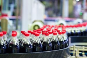 A photo showing a line of Coca-Cola bottles in a bottling plant.