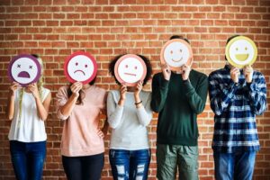 A photo showing a row of men and women holding different emotion signs in front of their faces.