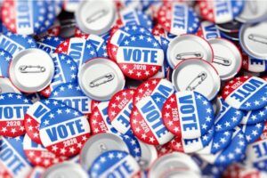 A photo of a pile of many red and blue “Vote 2020” buttons.