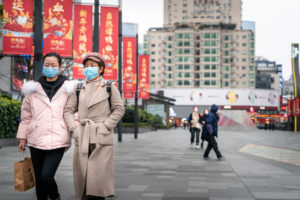 Two people walking while wearing face masks