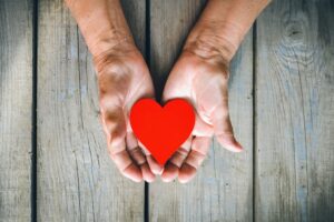 A photo showing a pair of hands holding a paper heart.