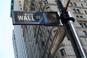 A photo showing the street signs at the intersection of Wall Street and Broadway.