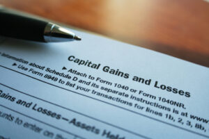 A photo showing the Capital Gains and Losses portion of the tax return forms on a table with a pen.