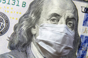 An image of a $100 U.S. bill with Benjamin Franklin wearing a medical mask.