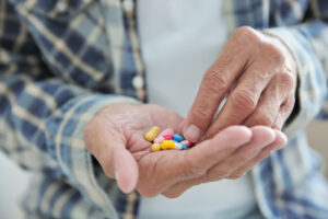 A photo showing a senior man’s hands holding many pills