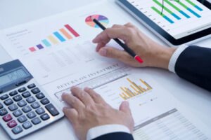 An image showing a businessman reviewing a variety of charts showing company performance, return on investment, etc.