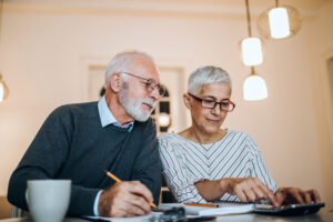 A photo showing a retired couple sitting together at a table working on their finances.