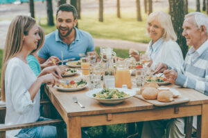 A photo of a family enjoying a meal together at an outside table.