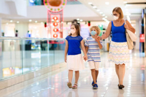 A photo showing a mother and two children at a shopping mall wearing masks.