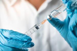 A photo showing a scientist drawing a vaccine from a bottle into a syringe.