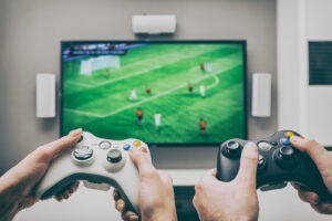 A photo showing two people playing a soccer video game on a large television.