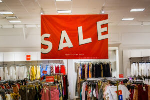 A “sale” sign hangs above a clothing store