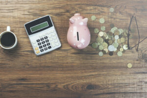 A piggy bank, calculator and cup of coffee