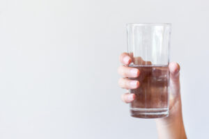 A woman holds a half-full glass of water