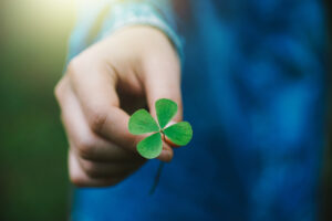 A close-up photo of a hand holding out a four-leaf clover.