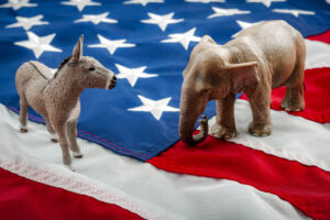 A donkey and an elephant face each other on an American flag, representing a face-off between Democrats and Republicans