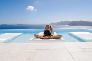 A woman relaxes next to a luxurious infinity pool