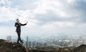 A blindfolded businessman steps dangerously close to a cliff