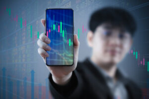 A photo of an investor holding up his smartphone to show a trading view graphic.