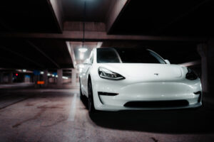 A white Tesla parked in a shadowy garage