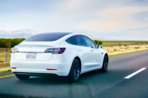 A white Tesla Model 3 driving on the freeway