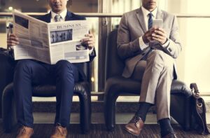 Two businessmen sit and read the news