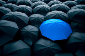 One blue umbrella stands out from a mass of black umbrellas