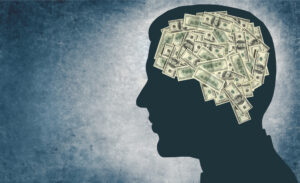 The outline of a person’s head with money on the brain