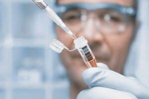 A scientist examines a drug sample in a vial