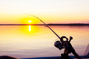 A fishing rod on the edge of a boat at sunset