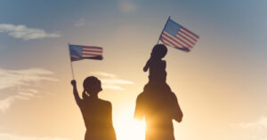 A family waves American flags in the sunset