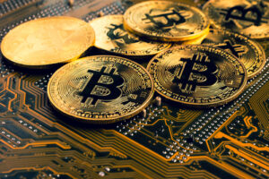 An image of several golden Bitcoin on top of a motherboard.