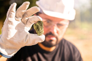 A gold miner holds up a gold nugget to examine it.