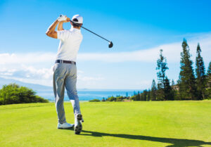 A golfer hits the ball with his club