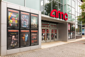 A front view of an AMC theater showing current movie posters on display.