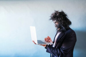 A photo of a man wearing a gorilla mask typing on a laptop.