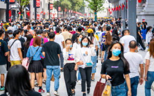 A photo of a crowded street in China showing many pedestrians wearing masks.