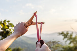 A photo showing hands using a slingshot to propel a small object.